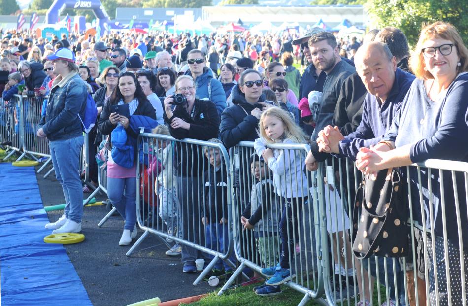 A crowd of family and friends wait for the competitors at the finish line.