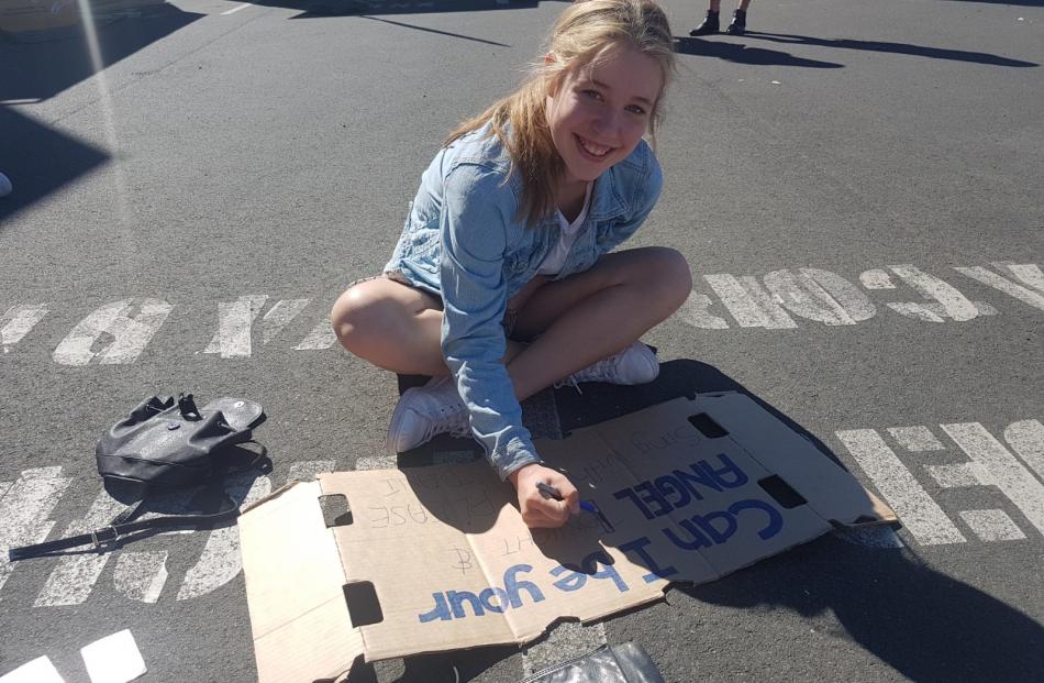 Dany Musgrave (13), of Christchurch, writes on a sign in the hopes Ed Sheran will invite him on...