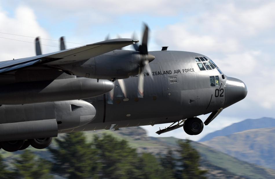 Visible in the front window, the pilot of the 34-tonne C-130 Hercules powers his plane into the...