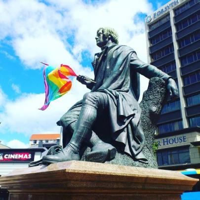 Robert Burns Statue holding a rainbow flag.