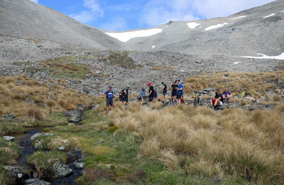 Riders take a break and replenish their supplies in an alpine stream. 