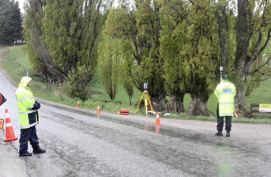 Constable Jack McGilbert (right), of the police serious crash unit, marks points on  the road as...