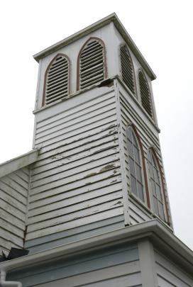 Rotting weatherboards and peeling paint on the exterior of the church.