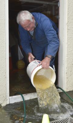 caretaker Allan Webber bails out a flooded cellar at the school