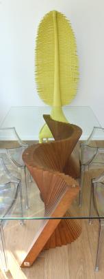 The wooden base for the dining table reflects the waves outside while a lime green chair has a...