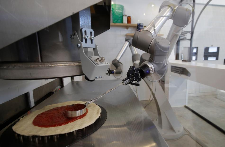 The robot prepares the base of the pizza with tomato sauce. Photo: Reuters 