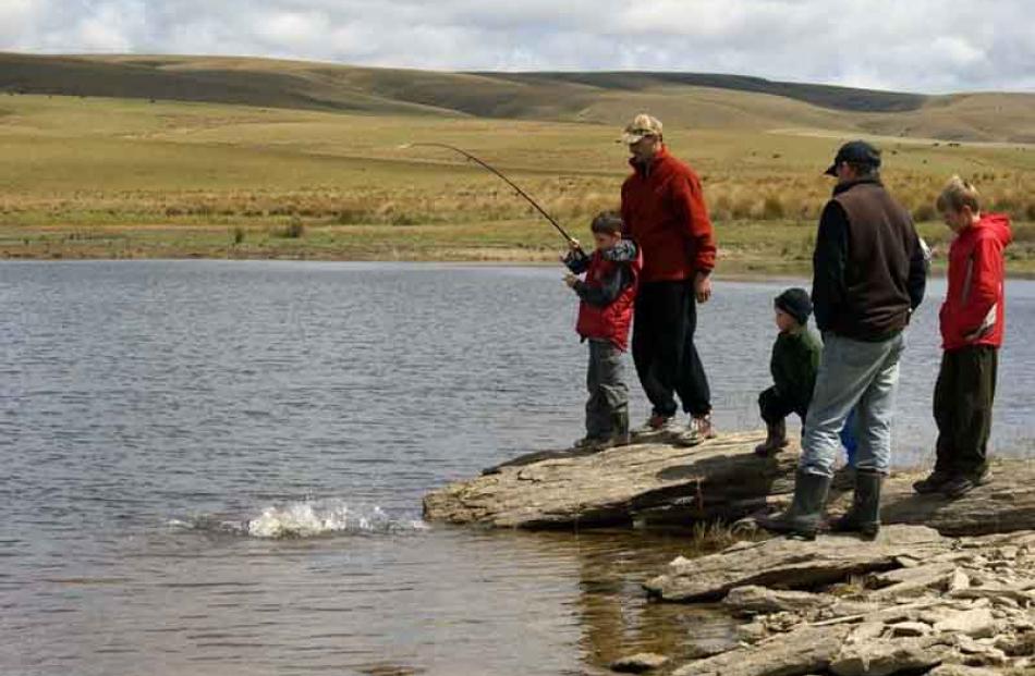 Online . . . Blake Mosley (8) brings in a trout at Lake Onslow on New Year's Day, supported by...