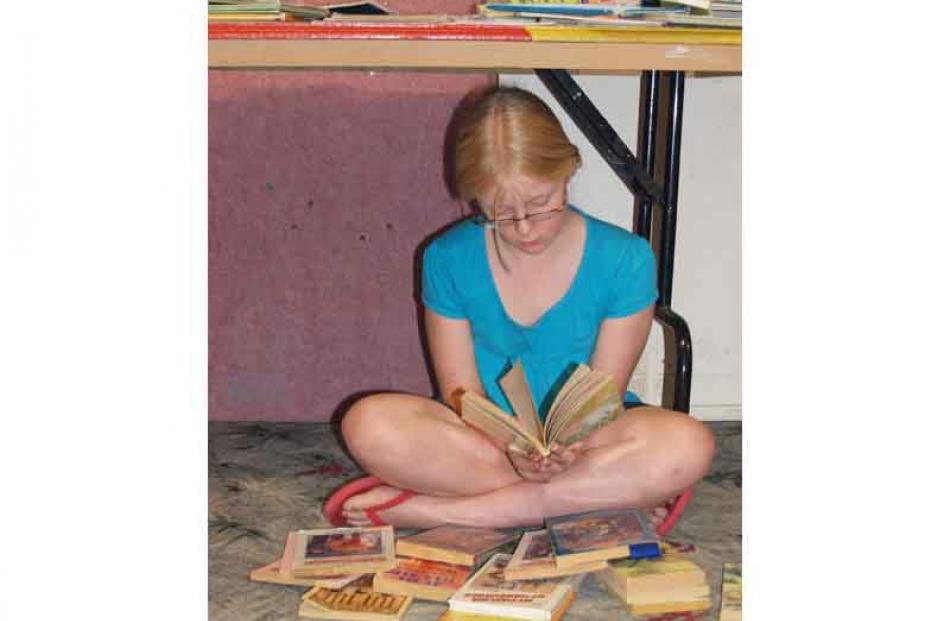 Bottom shelf . . . Caitlin Shaw (9), of Milton, settles with her selection from the Alexandra...