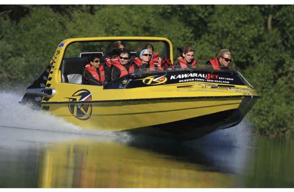 A Kawarua Jet boat skims the calm waters of the Kawarau River with a load of happy tourists. By...