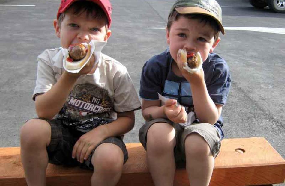 Sizzling . . . Cousins Billy and James Dougherty enjoy their sausages at a shop opening in...