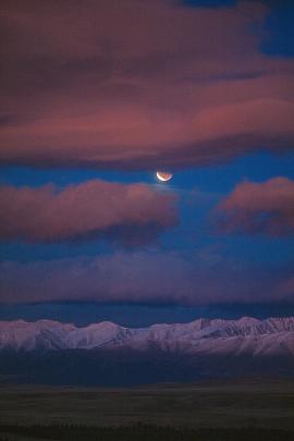 The lunar eclipse  peeps through the clouds high above the Southern Alps, taken from the Mt John...