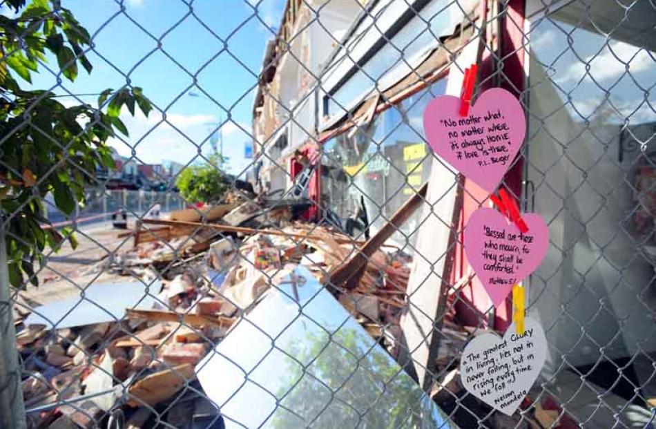Heart-shaped cards with inspirational messages have popped up on fences around rubble sites in...