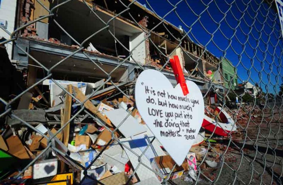 Heart-shaped cards with inspirational messages have popped up on fences around rubble sites in...