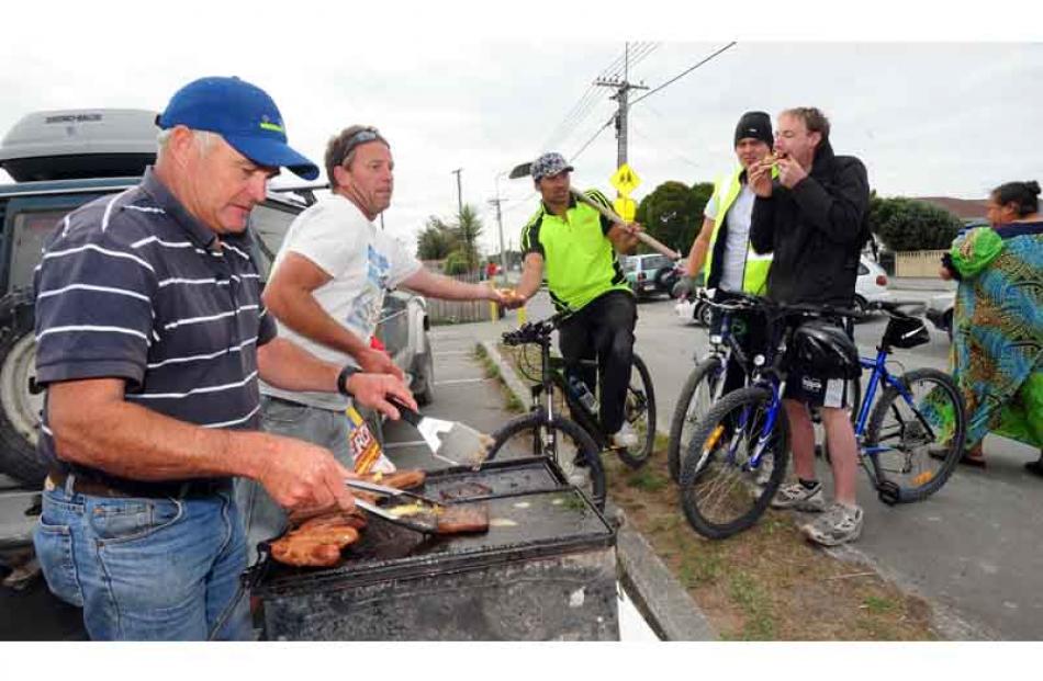Methven men Terry Hanson (left) and Dave Scammell cook up a feast for local volunteers (on bikes,...