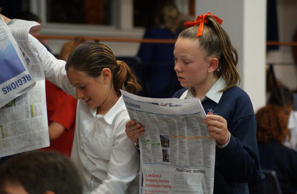 Sacred Heart Timaru pupils Maddy van Dipen (right) and Isobel Hill (both 12) browse through the Otago Daily Times during the year 7-8 current events quiz last night. Photo: Greta Yeoman