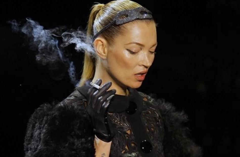 British model Kate Moss smokes a cigarette while modeling a creation by American fashion designer...