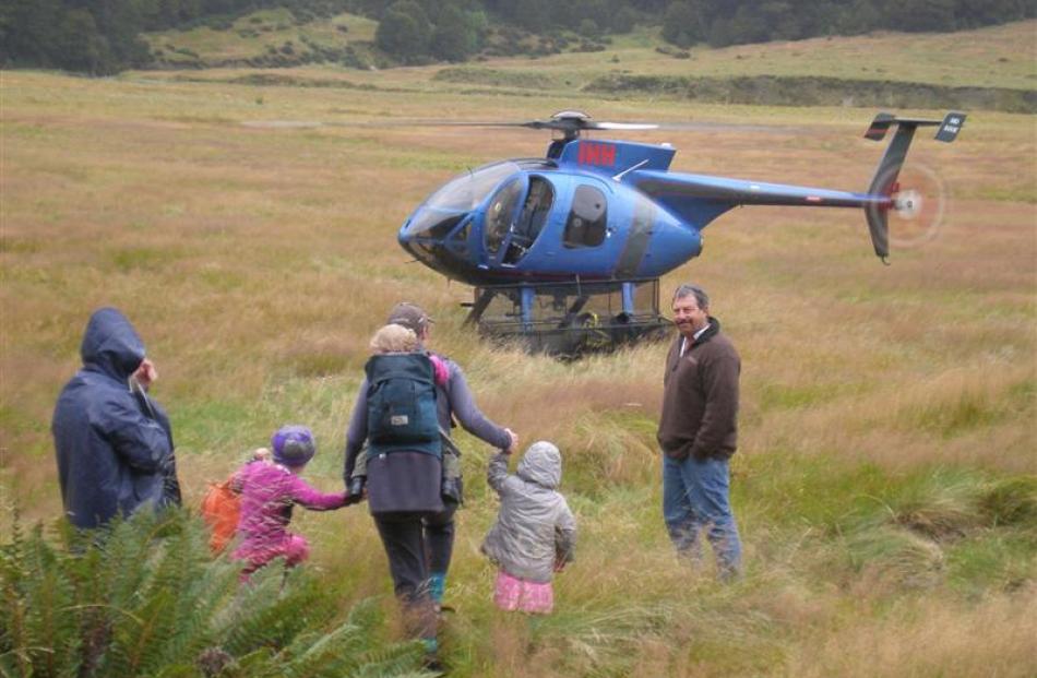 Trampers who had been staying in the hut head to a helicopter.
