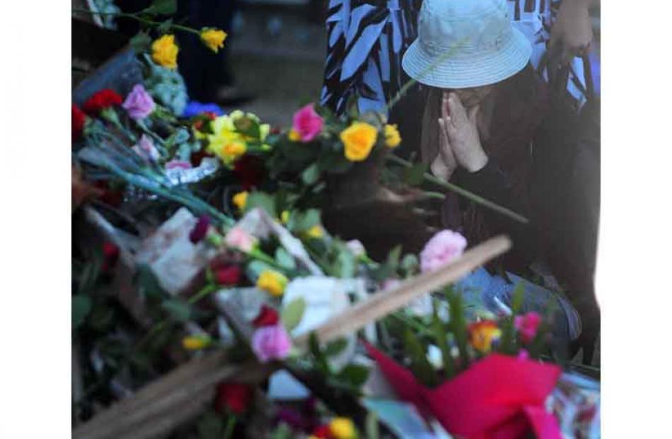 A Japanese woman prays after placing her flower.
