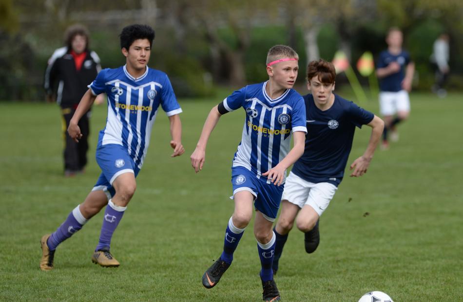 Christchurch United player Josh Sapsford (centre) looks upfield hunted by Cameron Paul, of Ferrymead Bays (right) while Marli Pradham (left) comes up in support. Photos: Linda Robertson