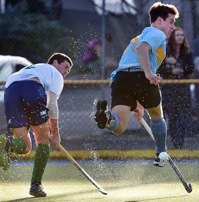 Spray kicked up from the wet ground is illuminated by low afternoon sun as Craig Turner (left), of Kings United, and Callum Dempster, of University, contest the ball during the men’s premier hockey final at the Alexander McMillan Turf in August. Photo: Pe