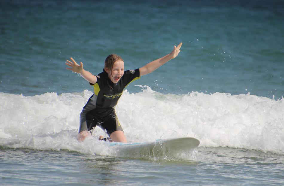 Ruby Merriman (10) finally gets up on her knees while trying out a friend’s surfboard on New Year...