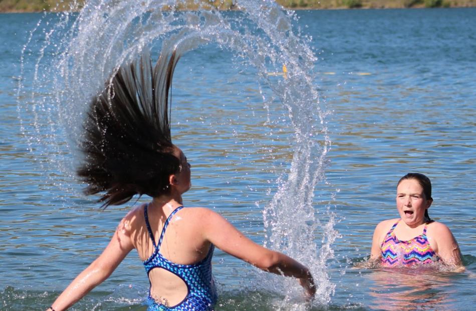 Anna Cowens (12) surprises her sister Sophie (11) with her water mohawk during a dip in Lake...