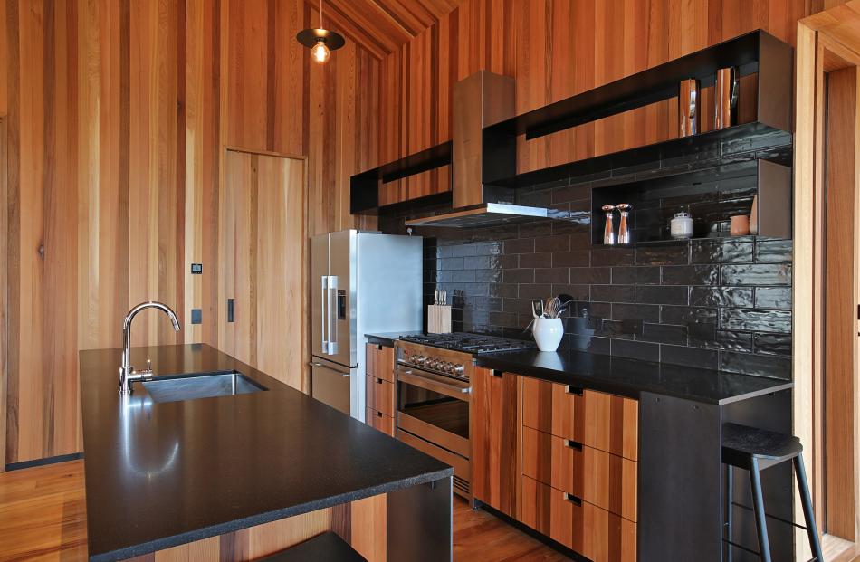 The kitchen has a honed Bengal black stone island and bench-top, band-sawn cedar joinery, glossy...