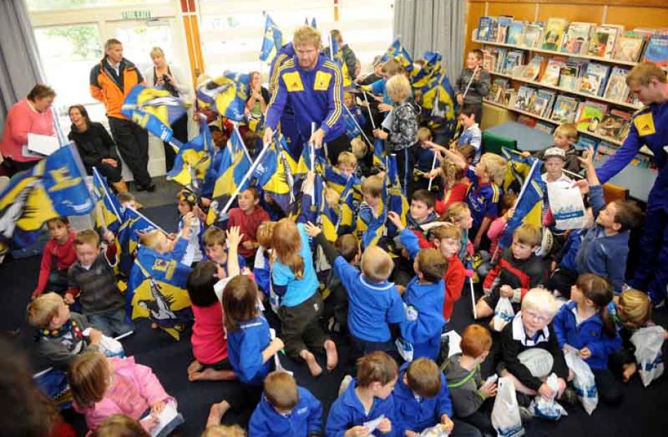 Adam Thompson hands out Highlanders flags to children at Heriot school.