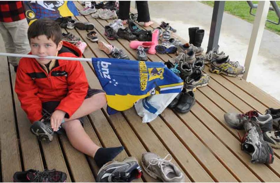 Hanging onto his flag in his teeth, Riley Hepi (6) of Riversdale school puts on his shoes.