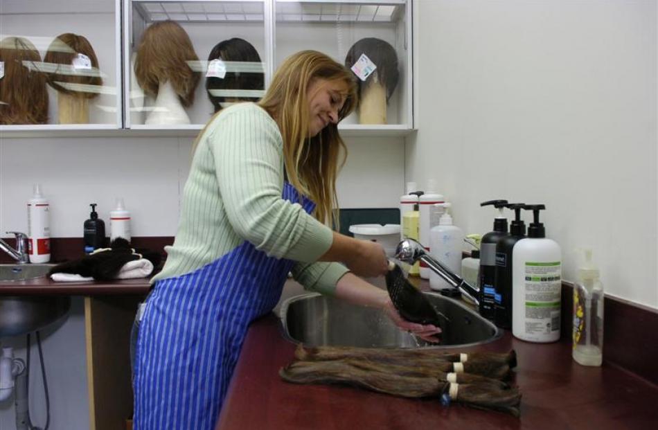 Kellie Anderson washes ponytails of hair.