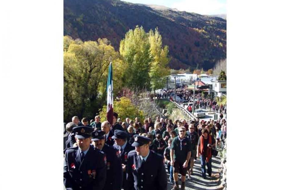 CAPTION: Reverent followers... Hundreds of people follow Arrowtown's ANZAC Day parade to the...