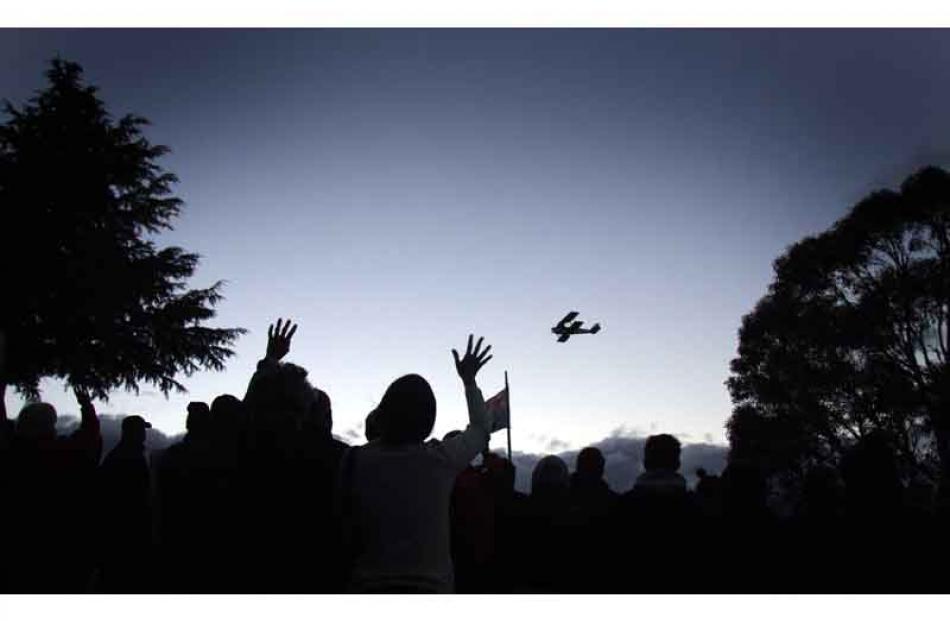 Dawn service . . . People wave to a tiger moth pilot during a flyover at the Lake Hawea Anzac Day...