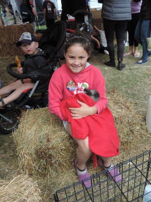 Keely Kubala (9) cuddles a rabbit at the Veterinary Centre pet tent, while an onlooker in a...