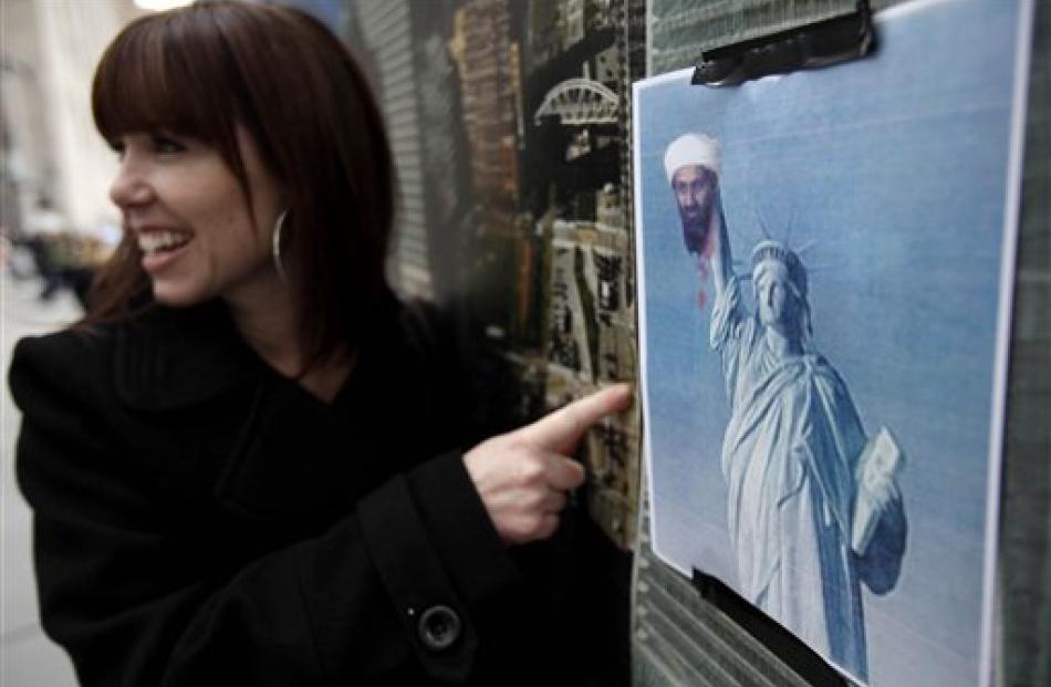 A tourist poses for a picture with a poster showing the Statue of Liberty holding the head of bin...