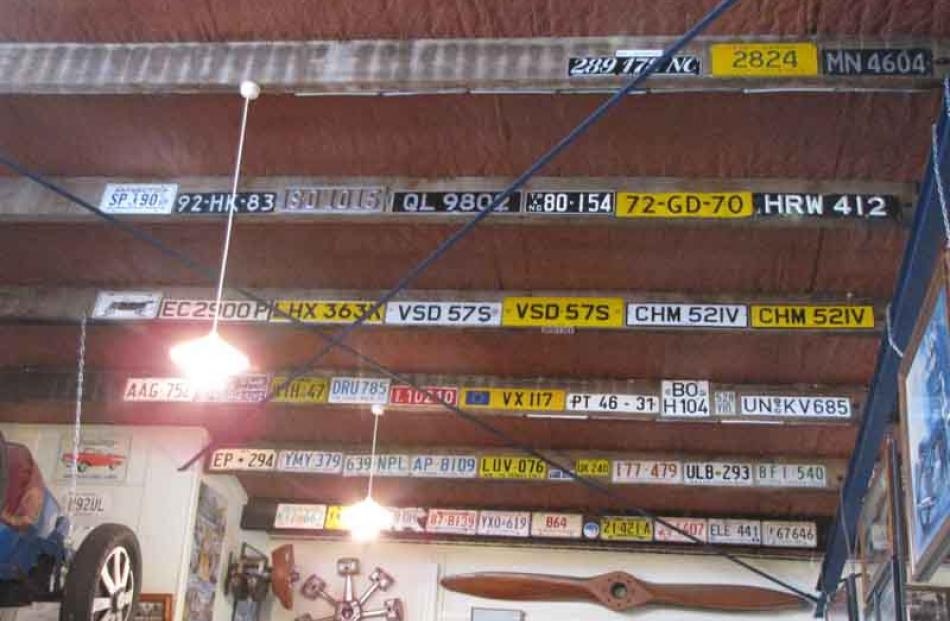 A collection of number plates affixed to rafters in John Taylor's private motor museum.