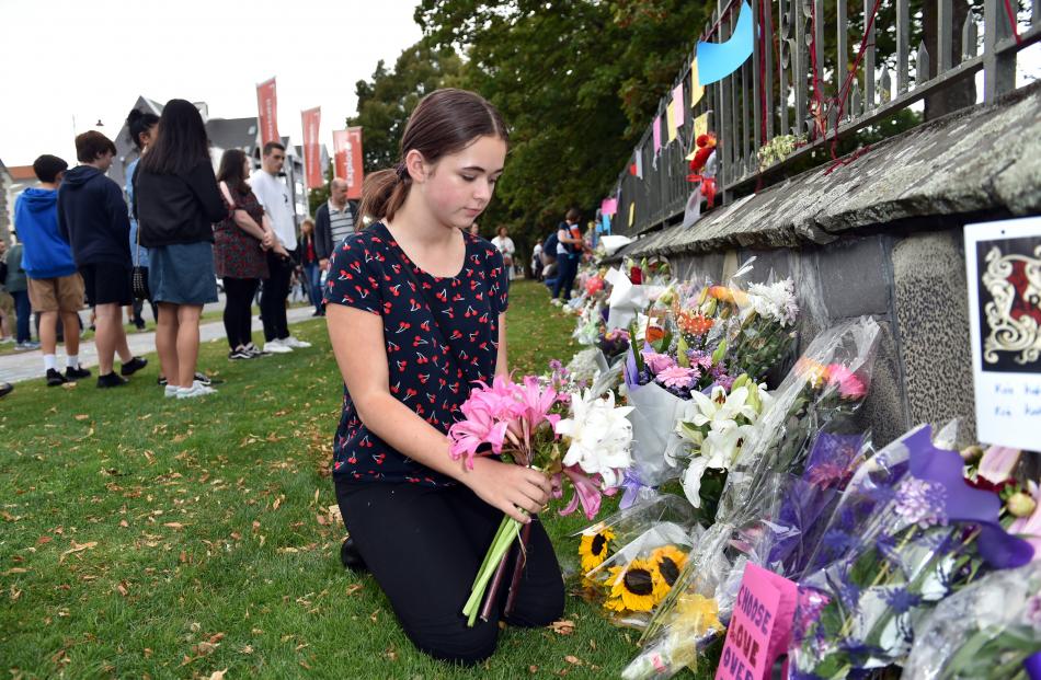 Eloise Piper lays flowers at a makeshift memorial near the Arts Centre on Saturday afternoon.
