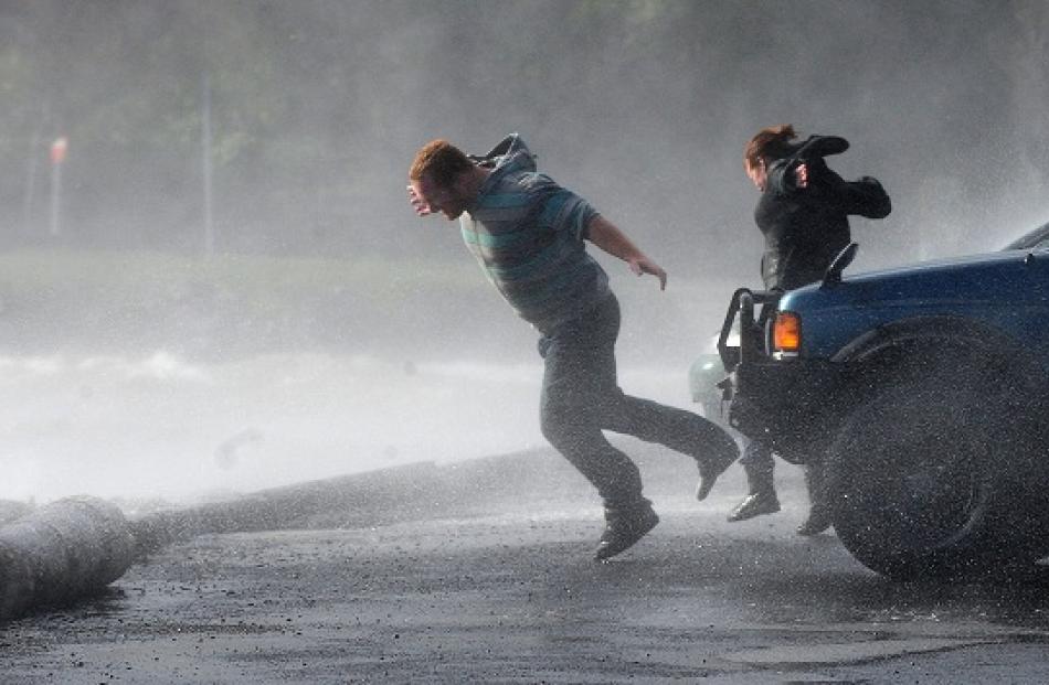 Pedestrians struggle against the wind at Macandrew Bay.