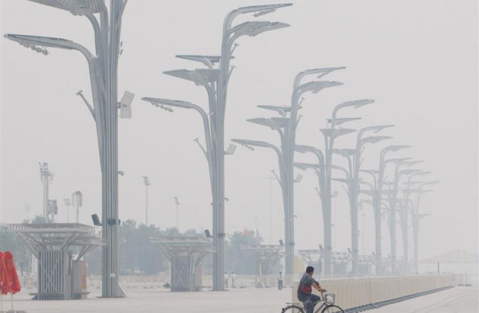 Haze is seen as a Chinese rides his bike past some lamp posts at Olympic park outside the...