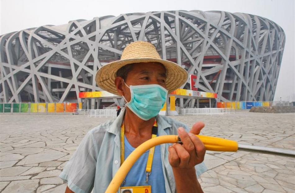 A Chinese worker wearing a mask cleans the pavement outside "birds nest", the National stadium at...