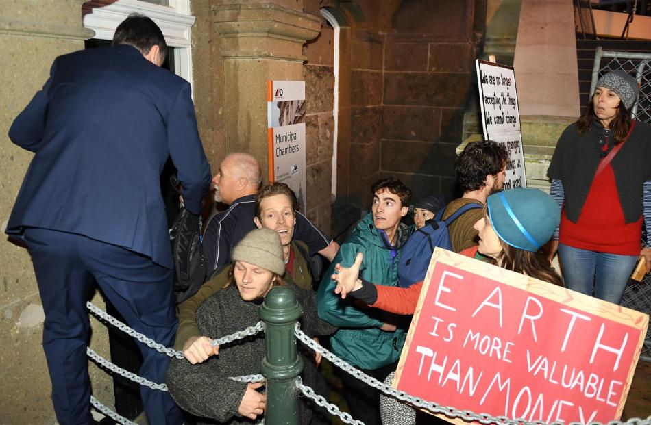 A delegate at the minerals forum tries to access the Dunedin Town Hall as protesters attempt to...