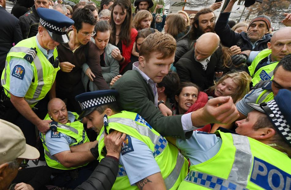 An officer loses his footing as police jostle with climate action protesters during one of...
