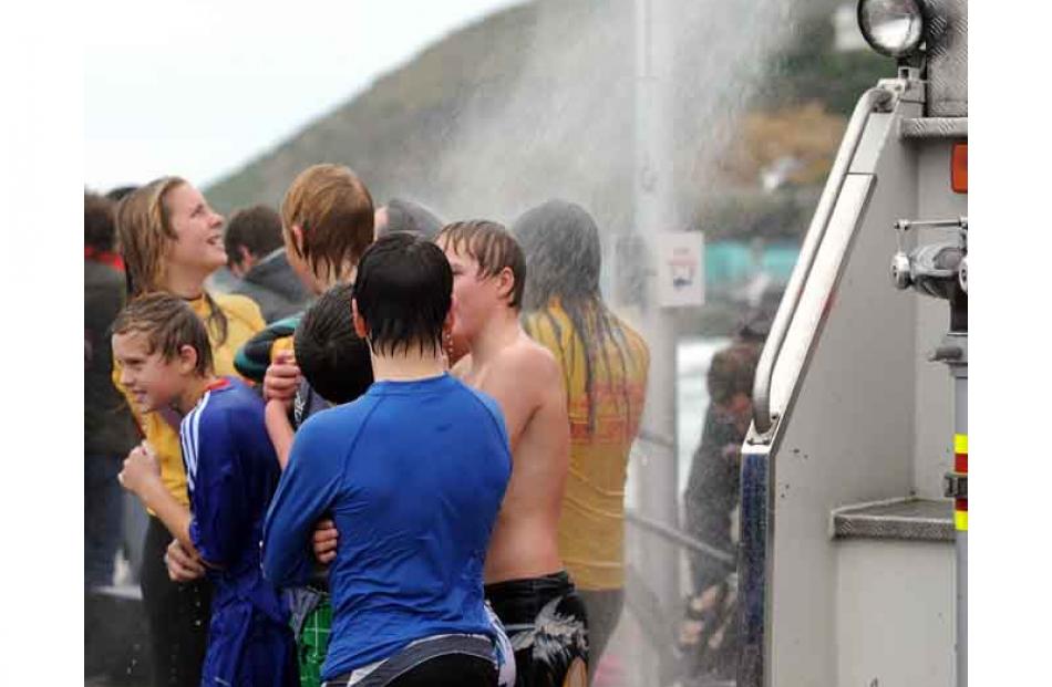 Warming up during the annual St Clair Beach 83rd midwinter polar plunge on Sunday. Photo by Peter...