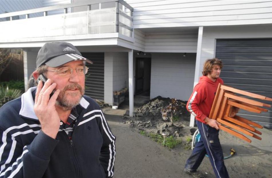 Phil Wenn (58) talks on the phone as Wade Askew (20) removes furniture from his Avonside home....