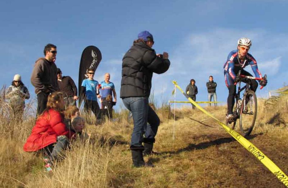 Spectators look on as Justin Price prepares to ride downhill.