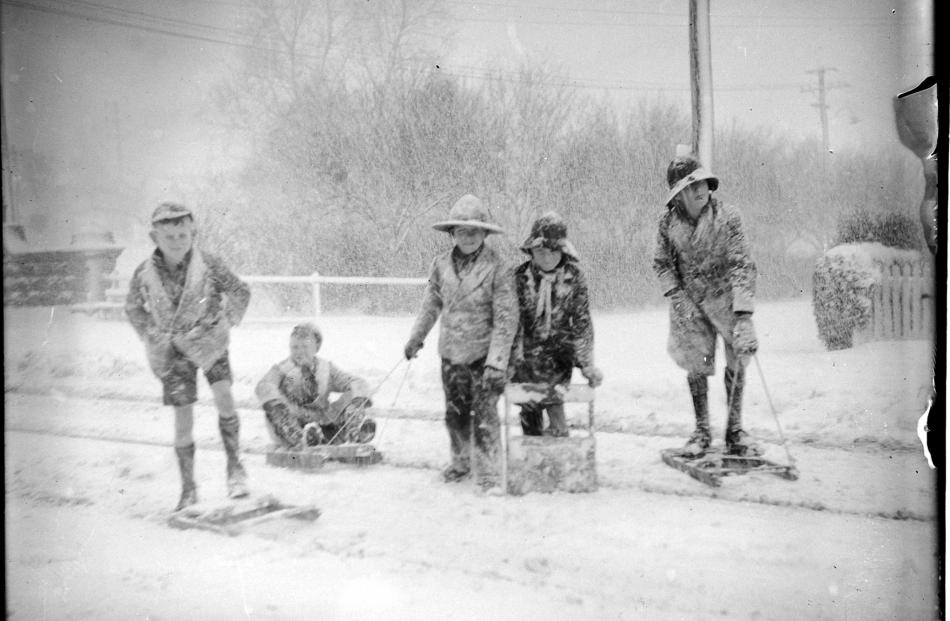 Children, some in shorts, play in the snow near the bridge at the north end of George St. PHOTO:...