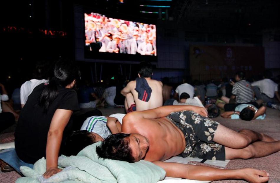 Chinese Olympic fans look at live public broadcasting of the opening ceremony. (AP Photo)