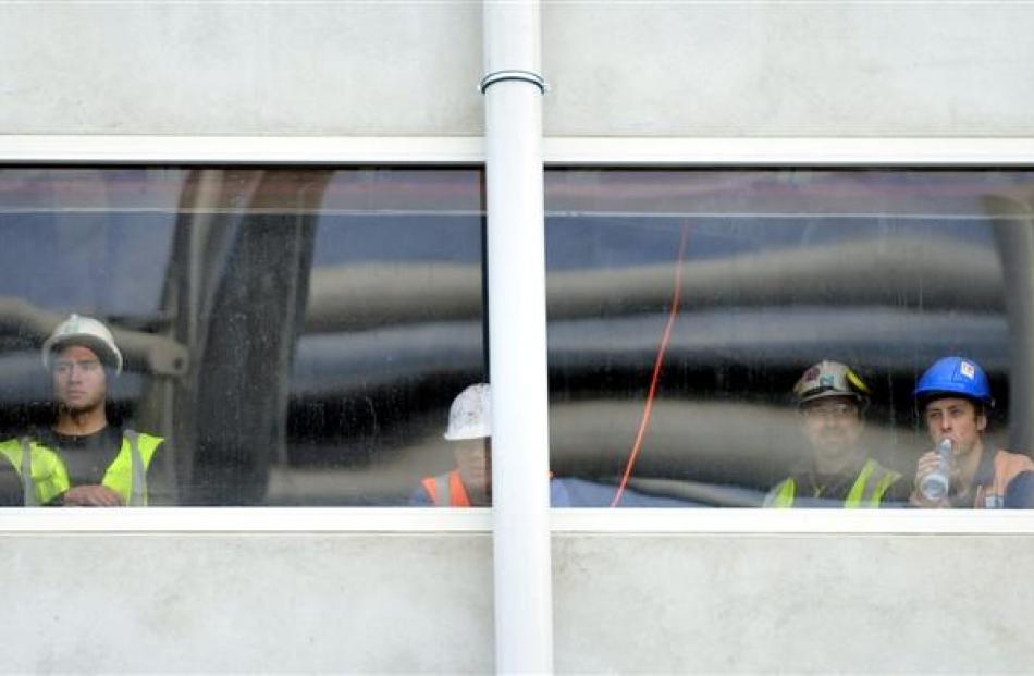 Construction workers watch the Selwyn-Knox match from a vantage point high up on the University...