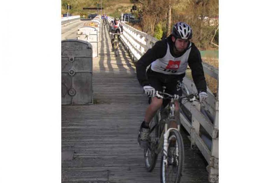 Winton resident Vaughan Gardyne, of team Rough and Ready, cycles across the Kawarau Bridge, with...