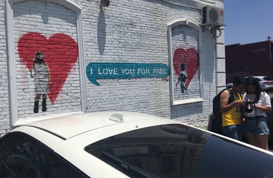 A couple inspect a "selfie" taken outside a street art mural in downtown LA's arts district....