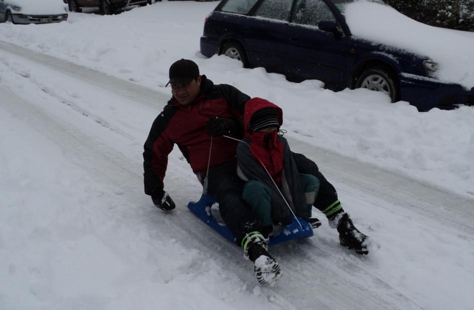 Cullen and Teeri (Dad) going down the street on the sled. Photo by Sally Carr.